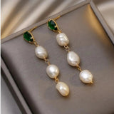 Golden earrings with a pearl and an emerald