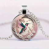 A hummingbird-shaped pendant necklace with a glass dome