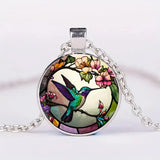 A hummingbird-shaped pendant necklace with a glass dome